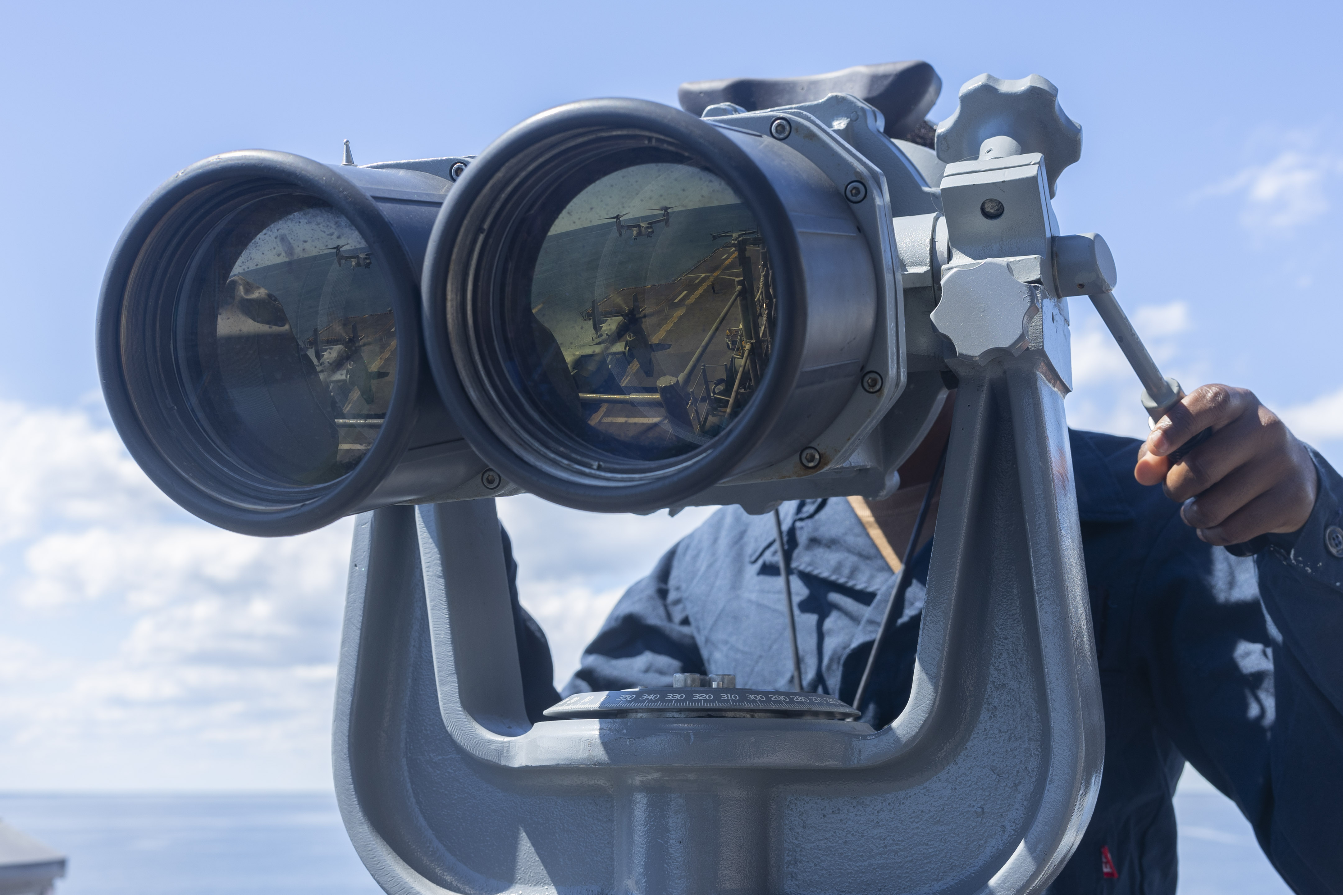 This is an image of a sailor looking through binoculars while on watch.